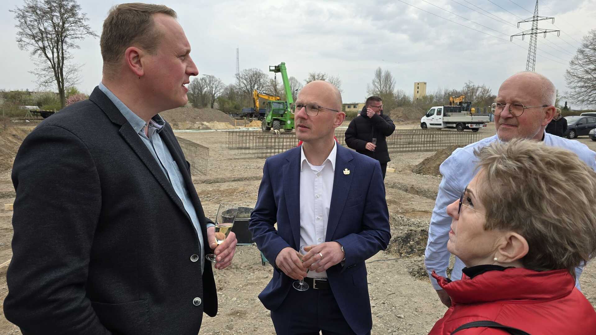 Gespräch bei Grundsteinlegung, Bauarbeiten im Hintergrund