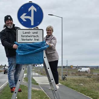 Zwei Personen an Verkehrsschild.