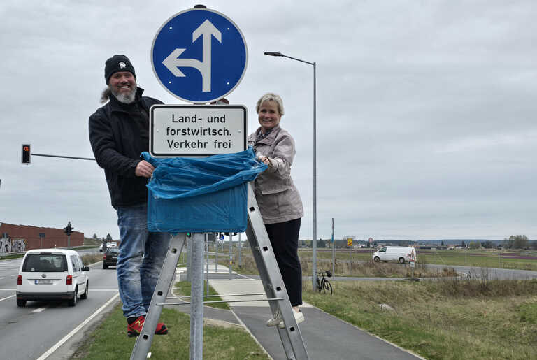 Zwei Personen an Verkehrsschild.