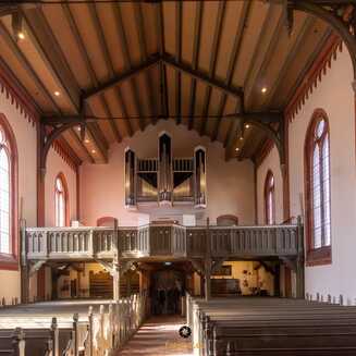 Helle Kirche mit Holzdecke und Orgel.
