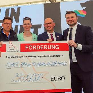 ICF-Weltcup 2026: Beetzsee als Highlight für den Kanusport - Fotobrb: Faszination Fotografie aus Brandenburg an der Havel Sportminister Hoffmann, Regattastreckenleiter Philipp, Beigeordnete Adel, Finanzminister Keller und OB Keip bei Scheckübergabe. © Stadt Brandenburg an der Havel / René Paul-Peters