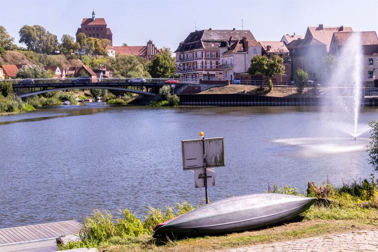 Ruhiger Fluss mit Boot und Stadt