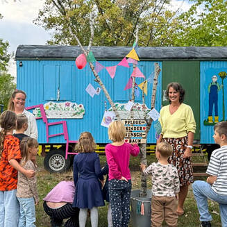 Die Mitarbeiterinnen Sophie Klee (links) und Simone Jacobi (rechts) des Pflegekinderdienstes mit den Kindern vor dem geschmückten Wunschbaum. © Stadt Brandenburg an der Havel / Pflegekinderdienst