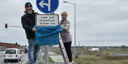 Zwei Personen an Verkehrsschild.